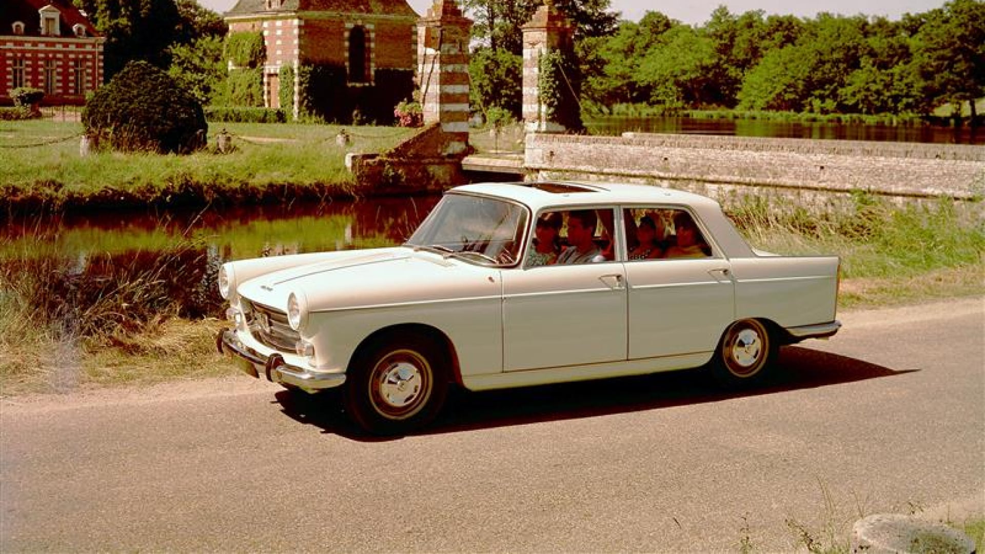 PEUGEOT 404 op een landweg voor een bakstenen kasteel en een tuin