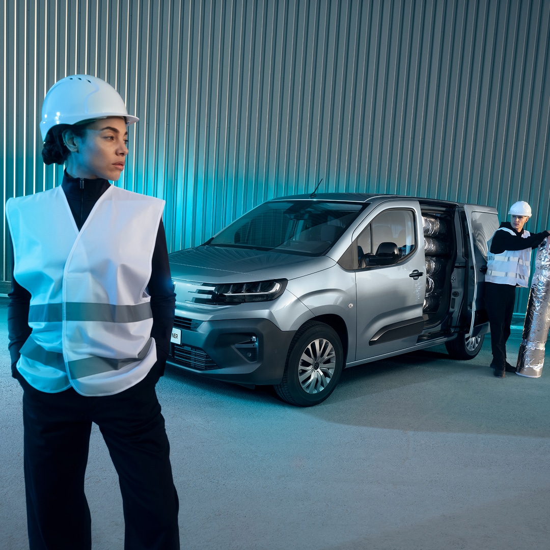 Een vrouw staat voor een PEUGEOT E-Partner